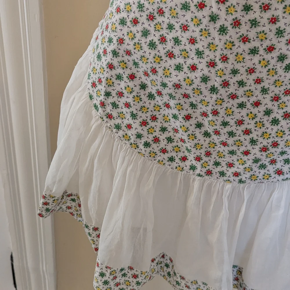 Vintage handmade white apron with red, green and red floral print.